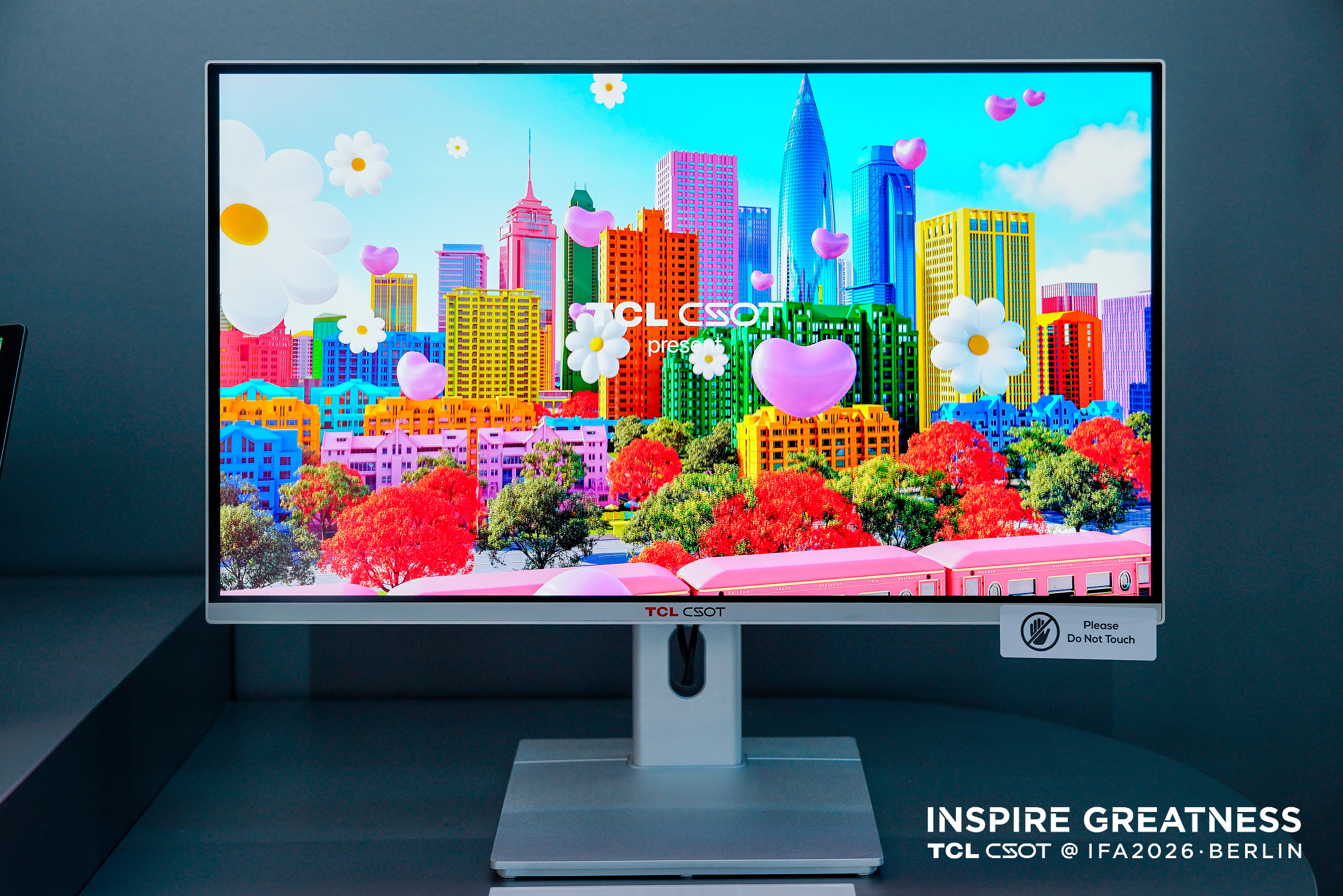 Moniteur de démonstration TCL CSOT à pied blanc affichant une ville colorée à l’IFA 2026.