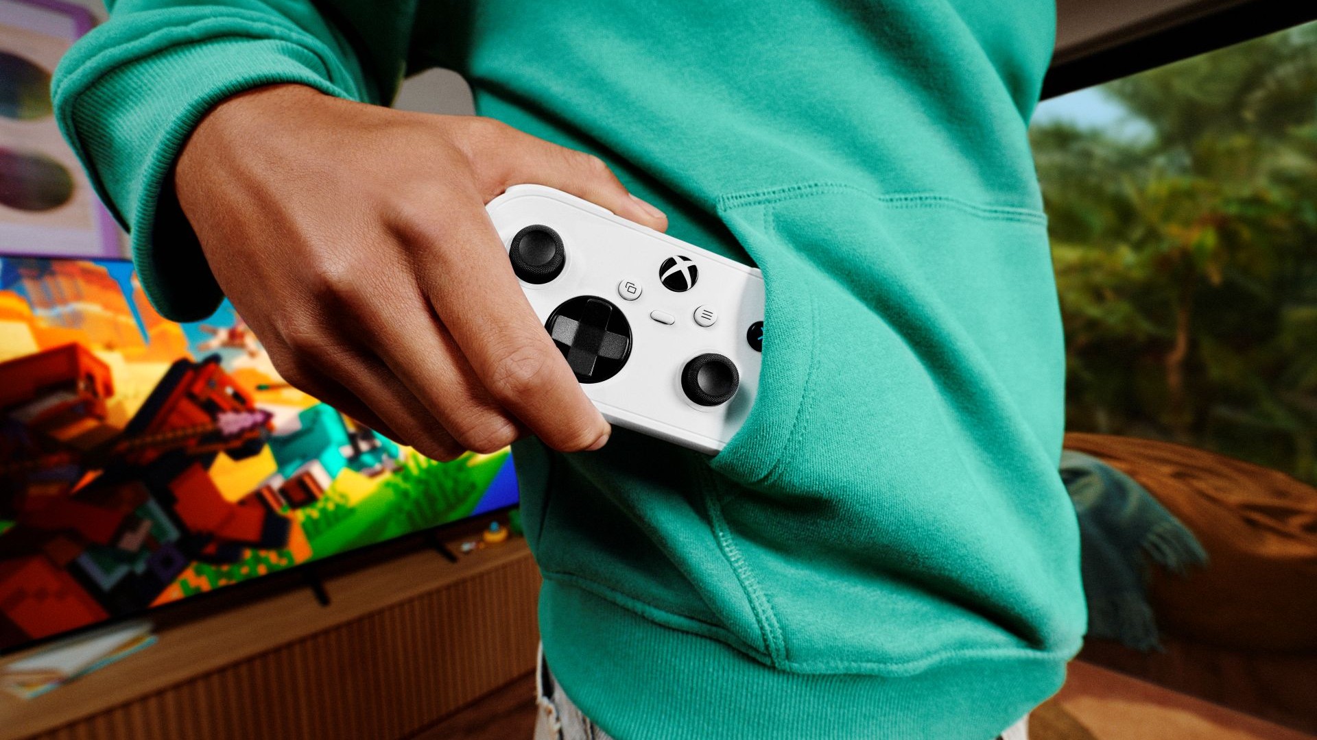Une Xbox Nano blanche glissée dans la poche avant d’un sweat-shirt vert.
