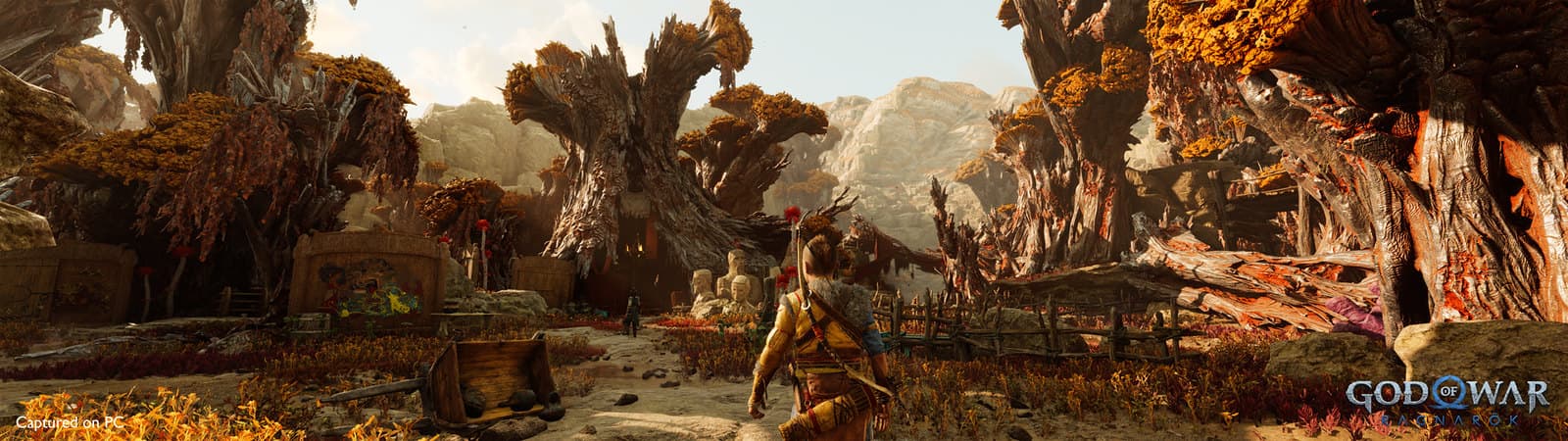 Atreus traverse les paysages boisés et lumineux de Jötunheim dans God of War Ragnarök.