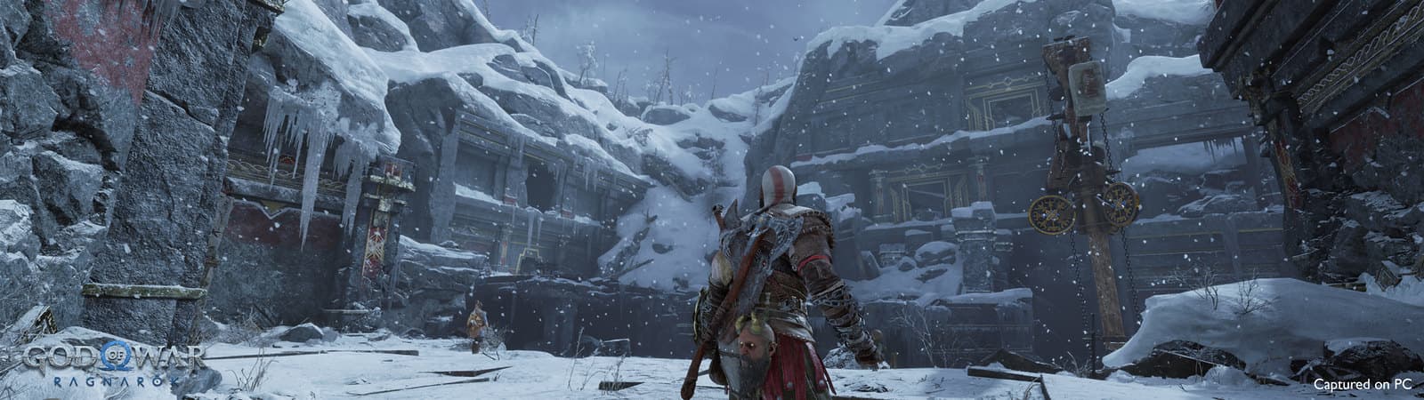 Kratos progresse dans des ruines enneigées présentées au format ultra-large sur PC.