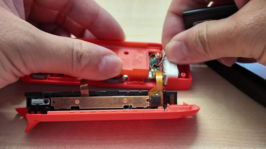 Déconnexion du câble de batterie dans un Joy-Con révisé selon la procédure Nintendo.