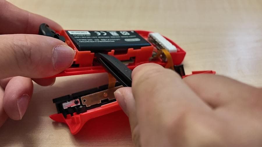 Retrait de la batterie d’un Joy-Con rouge dans le tutoriel officiel de Nintendo.