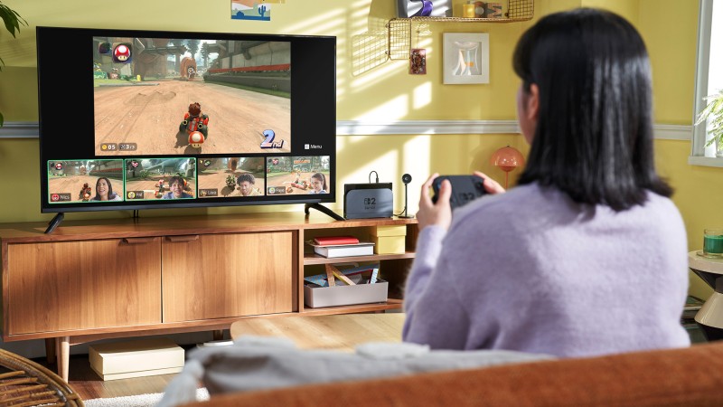 Joueuse utilisant une Nintendo Switch 2 sur un téléviseur avec plusieurs participants connectés.