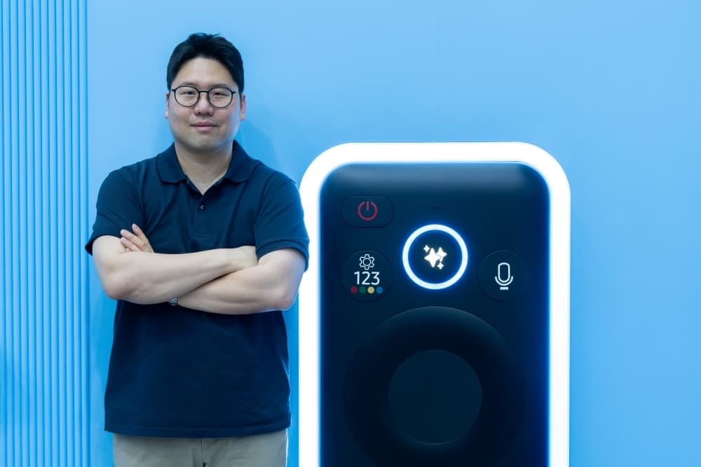 Responsable Samsung photographié à côté d’une représentation géante de la télécommande d’un téléviseur connecté.