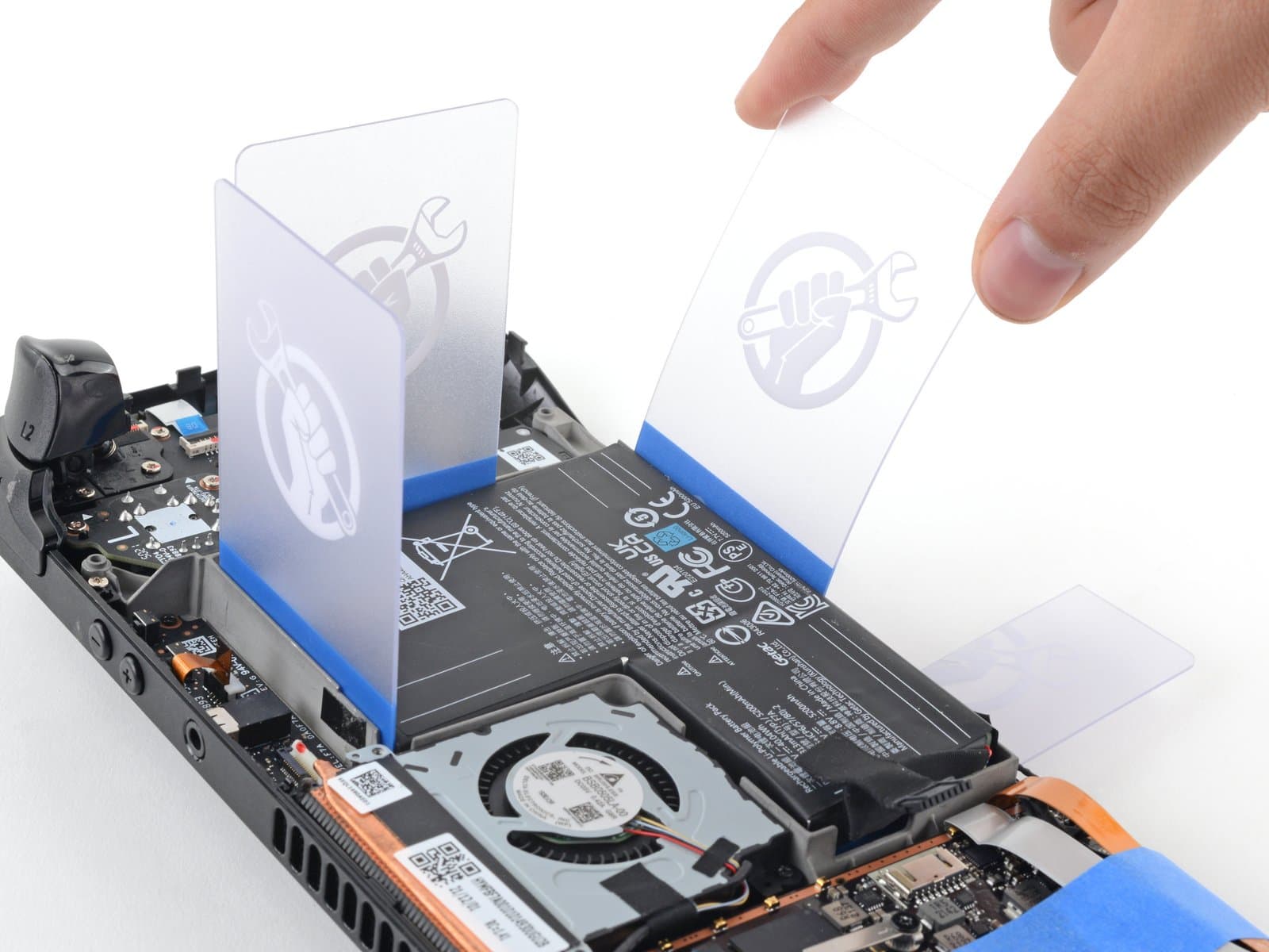 Plusieurs cartes d’ouverture iFixit placées autour de la batterie collée du Steam Deck LCD.