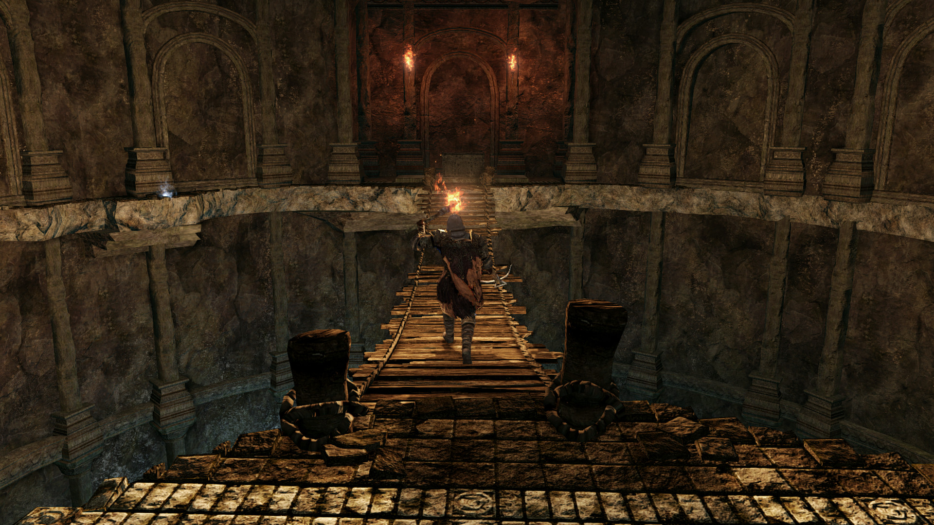 Un personnage traverse une passerelle suspendue dans un souterrain.