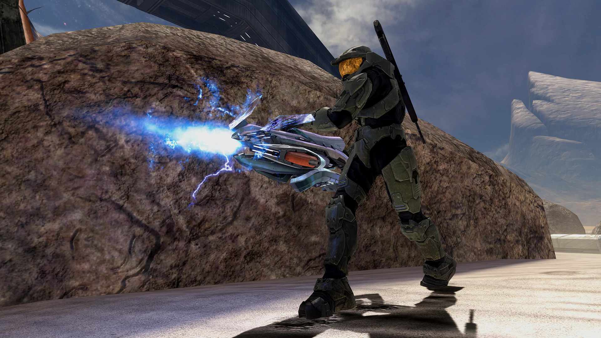 Halo 3 dans MCC : un Spartan fait feu avec une arme à énergie près d’un rocher.