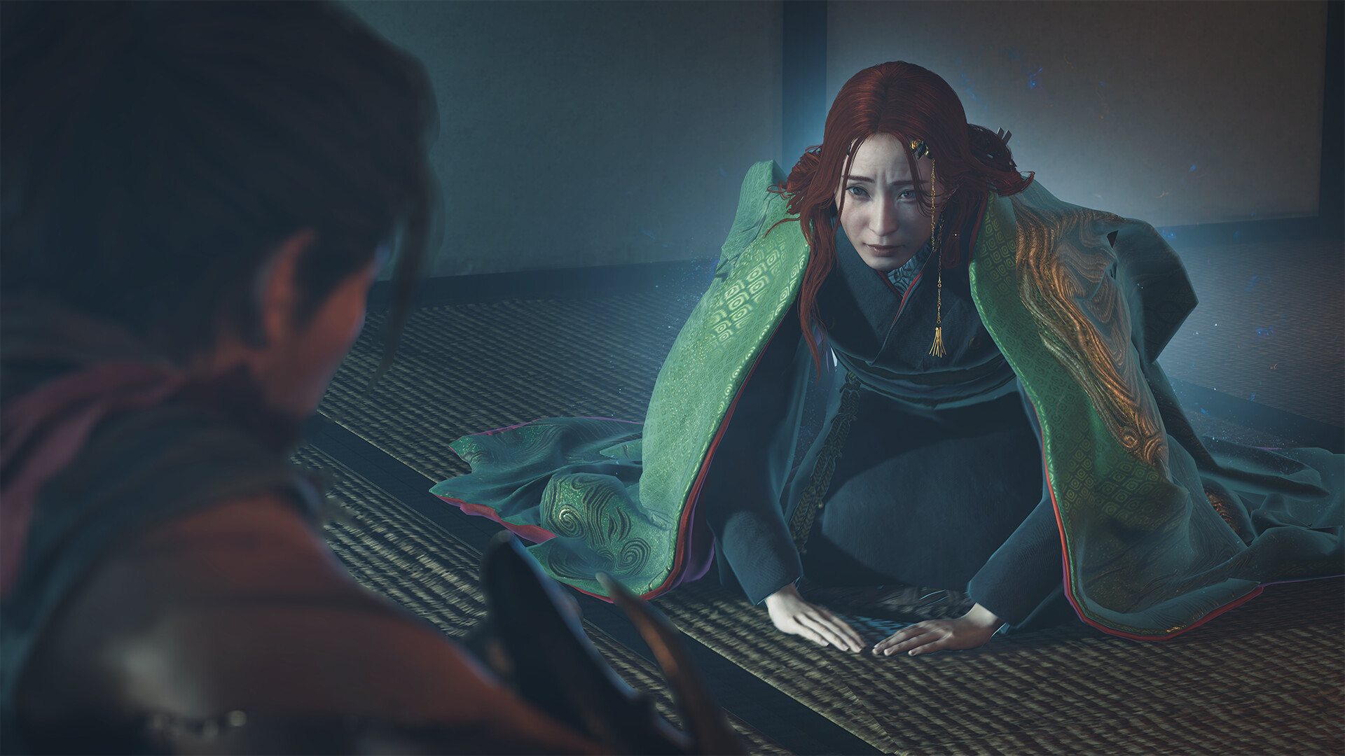 Une femme en tenue verte s’adresse à un personnage assis.