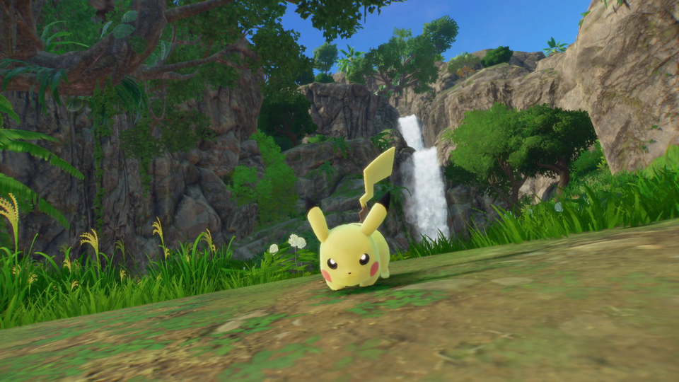 Un Pikachu se tient dans l’herbe près d’une cascade.
