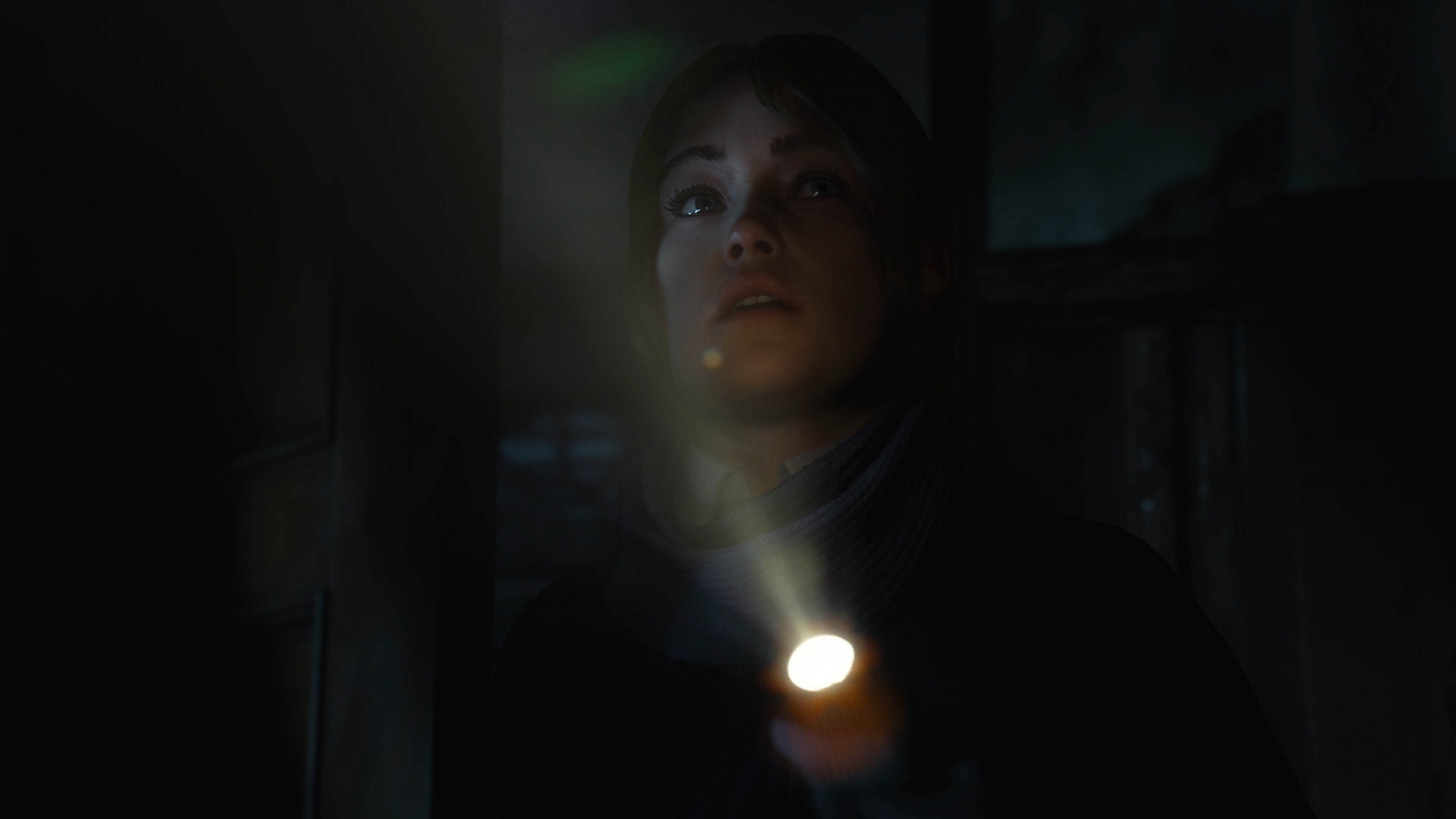 Une femme explore l’obscurité à la lumière d’une torche.